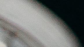 Foto referencial de una mano sosteniendo una hoja de papel en blanco junto a una laptop