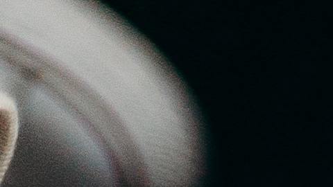Foto referencial de una mano sosteniendo una hoja de papel en blanco junto a una laptop