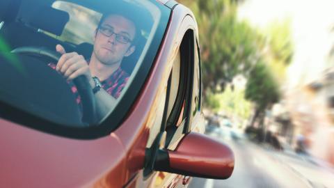 Foto de hombre conduciendo un auto rojo
