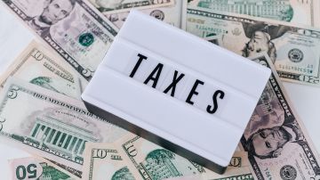 Foto de billetes dispersos en una mesa con un letrero que muestra la palabra "taxes"