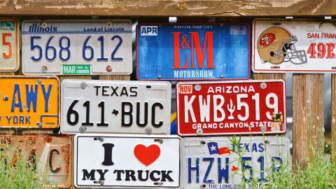 Foto de un muro con varias placas de matrícula colgadas.