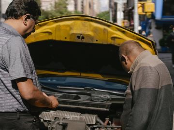 Mecánico, y su cliente, revisando un auto usado