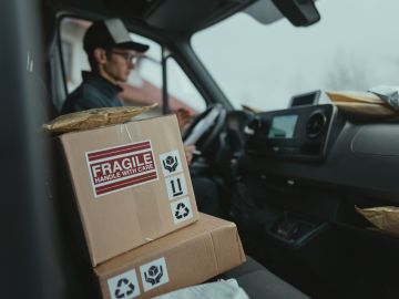 Foto de un repartidor en la cabina de un camión de entrega con paquetes