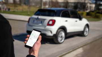 Foto de un usuario usando su celular para comunicarse con su Fiat 500 "Hey Google"