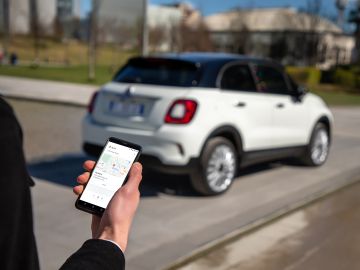 Foto de un usuario usando su celular para comunicarse con su Fiat 500 "Hey Google"