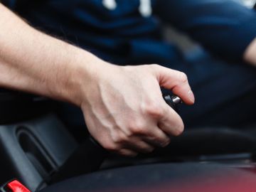 Foto de la mano de un hombre operando el freno de mano de su vehículo