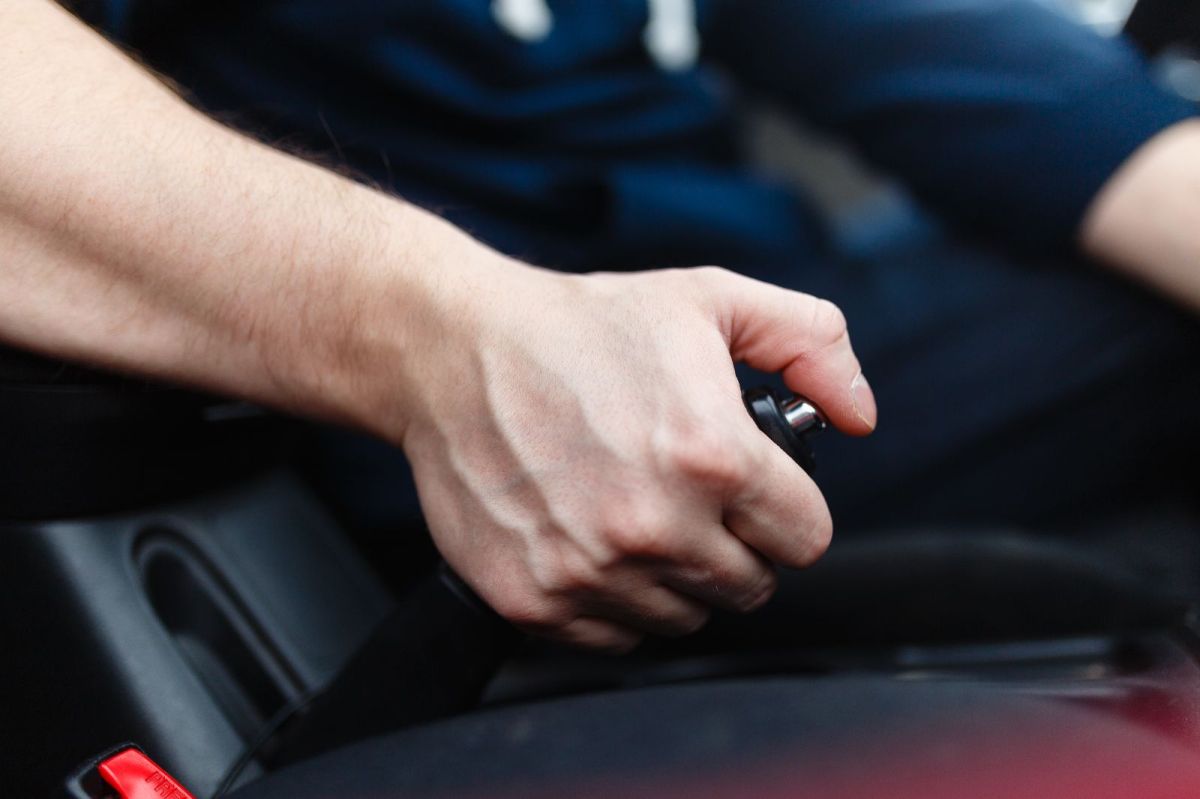 Image of a man's hand operating the parking brake of his car