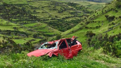 Foto de un auto destruido y abandonado a un lado de la carretera