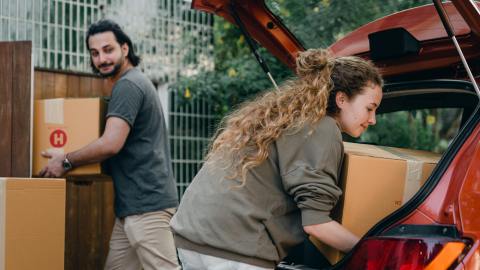 Foto de una pareja sacando paquetes de su auto en plena mudanza