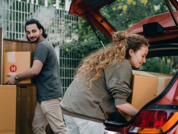 Foto de una pareja sacando paquetes de su auto en plena mudanza