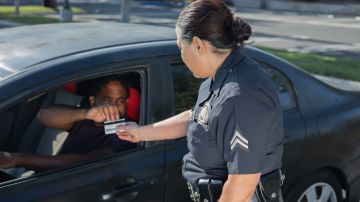 Foto de una oficial de policía solicitando una licencia de conducir a un conductor