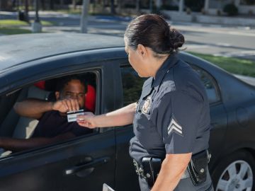 Foto de una oficial de policía solicitando una licencia de conducir a un conductor
