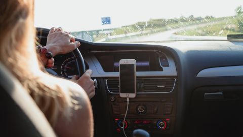 Foto de una mujer mientras conduce tomada desde el asiento de atrás.