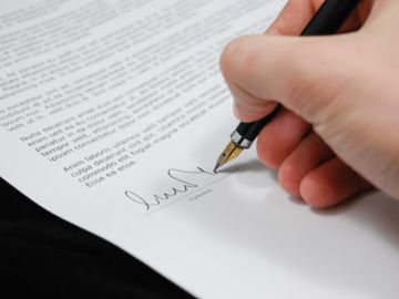 Foto de la mano de una persona firmando unos documentos