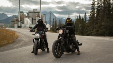 Foto de dos motociclistas con sus cascos estacionados en plena vía