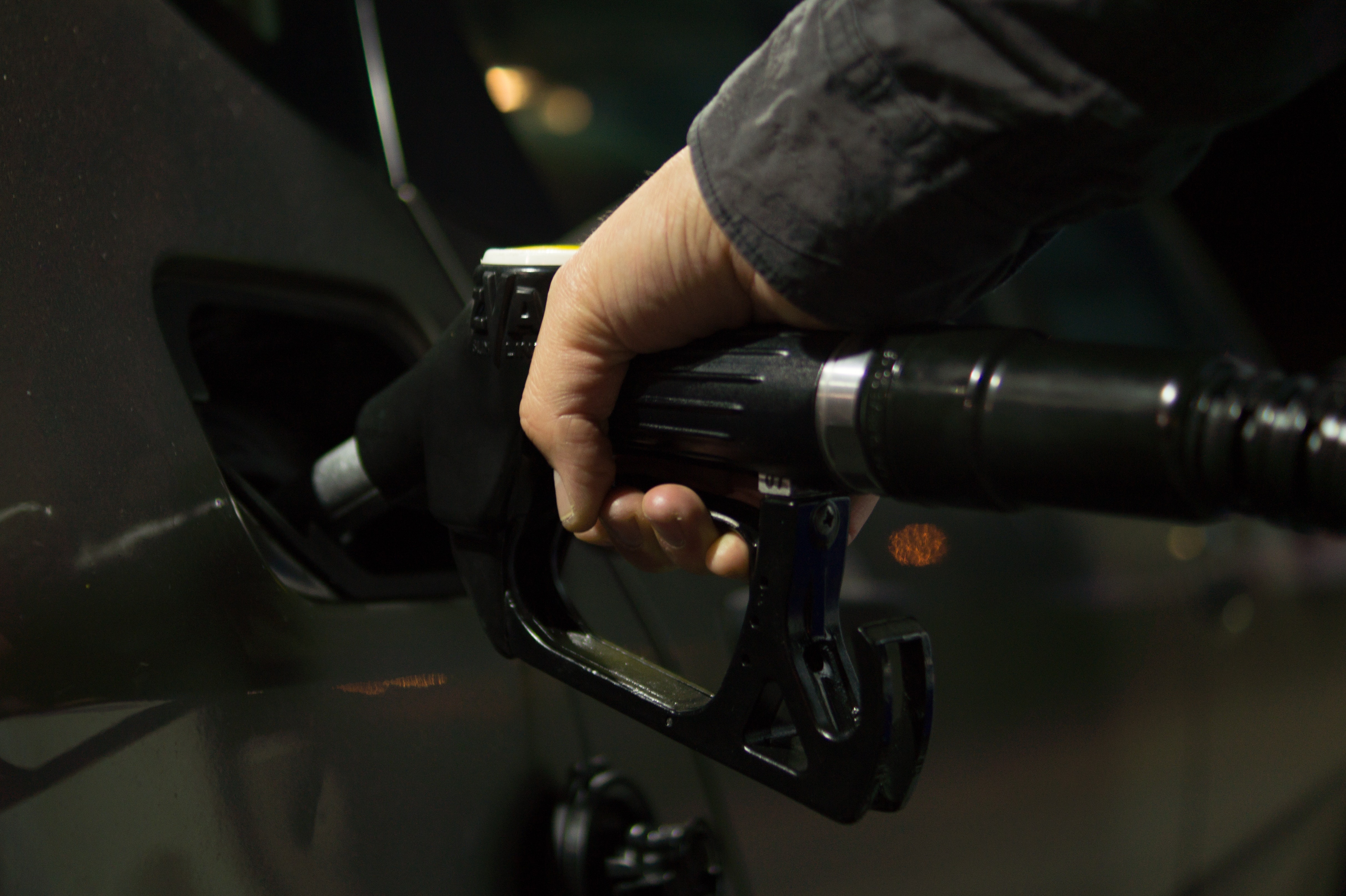 Foto de la mano de una persona poniendo combustible a un auto en una estación de servicio