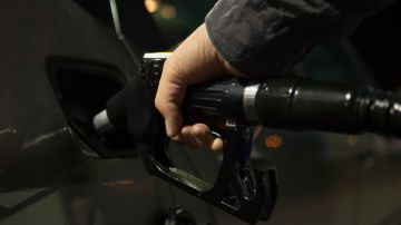 Foto de la mano de una persona poniendo combustible a un auto en una estación de servicio