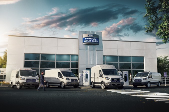 Foto de la línea de furgonetas E-Transit de Ford estacionadas frente a un centro de servicio