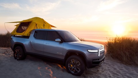 Foto de la camioneta eléctrica R1T de Rivian con una tienda de campaña en la zona de carga