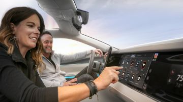 Foto de dos personas dentro de la cabina de un auto operando una pantalla inteligente