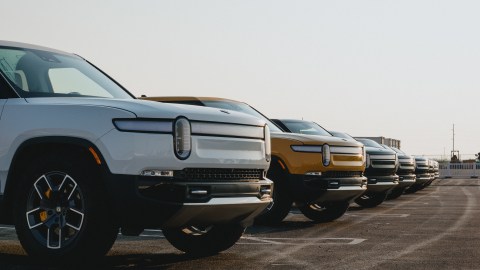 Foto de una línea de camionetas R1T de Rivian estacionadas al aire libre