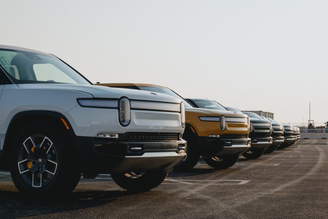 Foto de una línea de camionetas R1T de Rivian estacionadas al aire libre