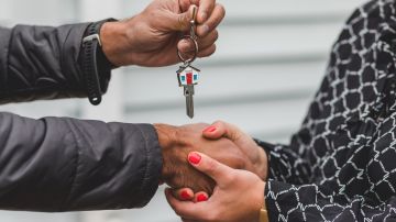 Foto de una persona entregando las llaves de una casa a otra persona