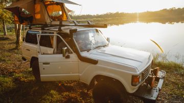 Foto de un auto de aventura estacionado cerca de un lago