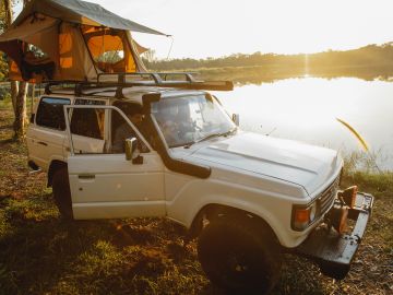 Foto de un auto de aventura estacionado cerca de un lago
