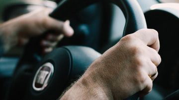 Foto de la mano de una persona sobre el volante de un auto mostrando el tablero de fondo