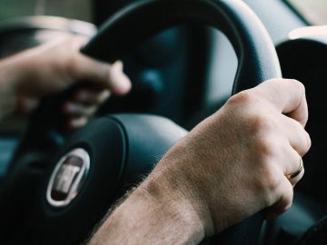 Foto de la mano de una persona sobre el volante de un auto mostrando el tablero de fondo