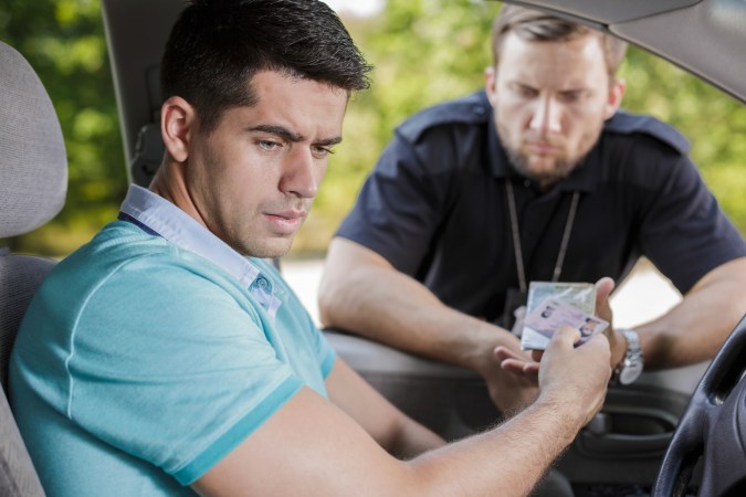 Foto de un conductor entregando su licencia de conducir a un policía