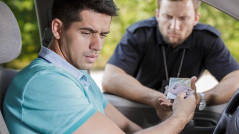 Foto de un conductor entregando su licencia de conducir a un policía