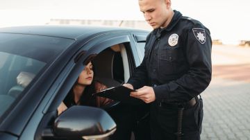 Foto de un policía asignándole una boleta a una mujer que conduce