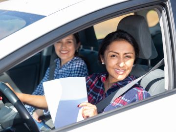 Foto de una mujer conduciendo con documentos en la mano