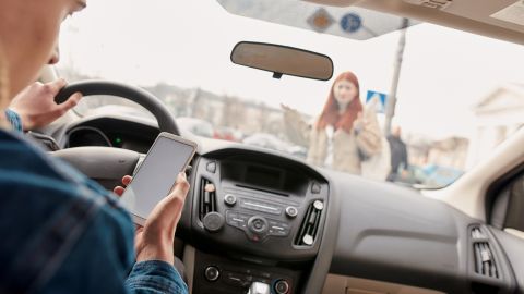 Foto de un conductor usando un teléfono mientras opera un auto