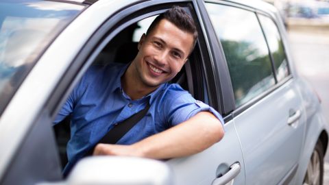 Foto de un conductor sonriendo desde la ventana del auto