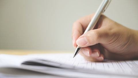 Foto de la mano de una persona completando un formulario