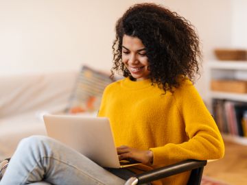 Foto de una mujer sonriendo mientras usa una laptop