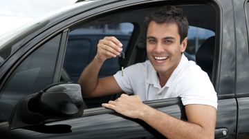 Foto de un conductor sonriendo desde la ventana del auto mostrando una llave
