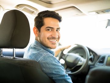 Foto de un conductor sonriendo en el interior de un auto