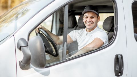 Foto de una hombre sonriendo desde la cabina de un camión