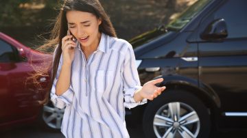 Foto de una mujer hablando por teléfono luego de un accidente de tránsito