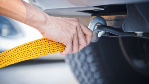 Foto de la mano de un operador de grúa enganchando un auto