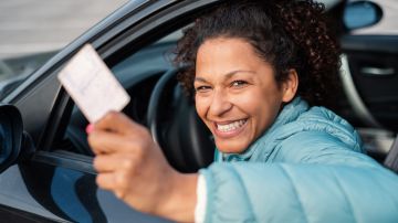Foto de una mujer mostrando su licencia mientras sonríe