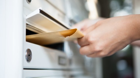 Foto de la mano de una persona dejando documentos en un buzón de correo