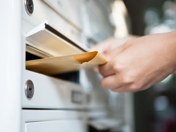 Foto de la mano de una persona dejando documentos en un buzón de correo