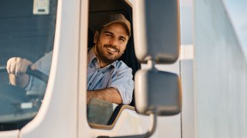 Foto de un camionero sonriendo mientras conduce