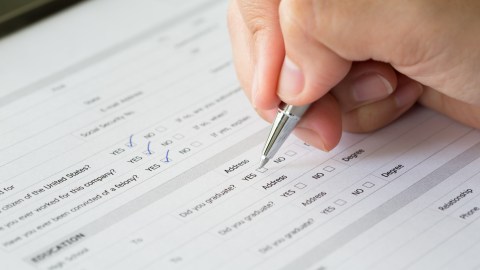 Foto de la mano de una persona completando un formulario