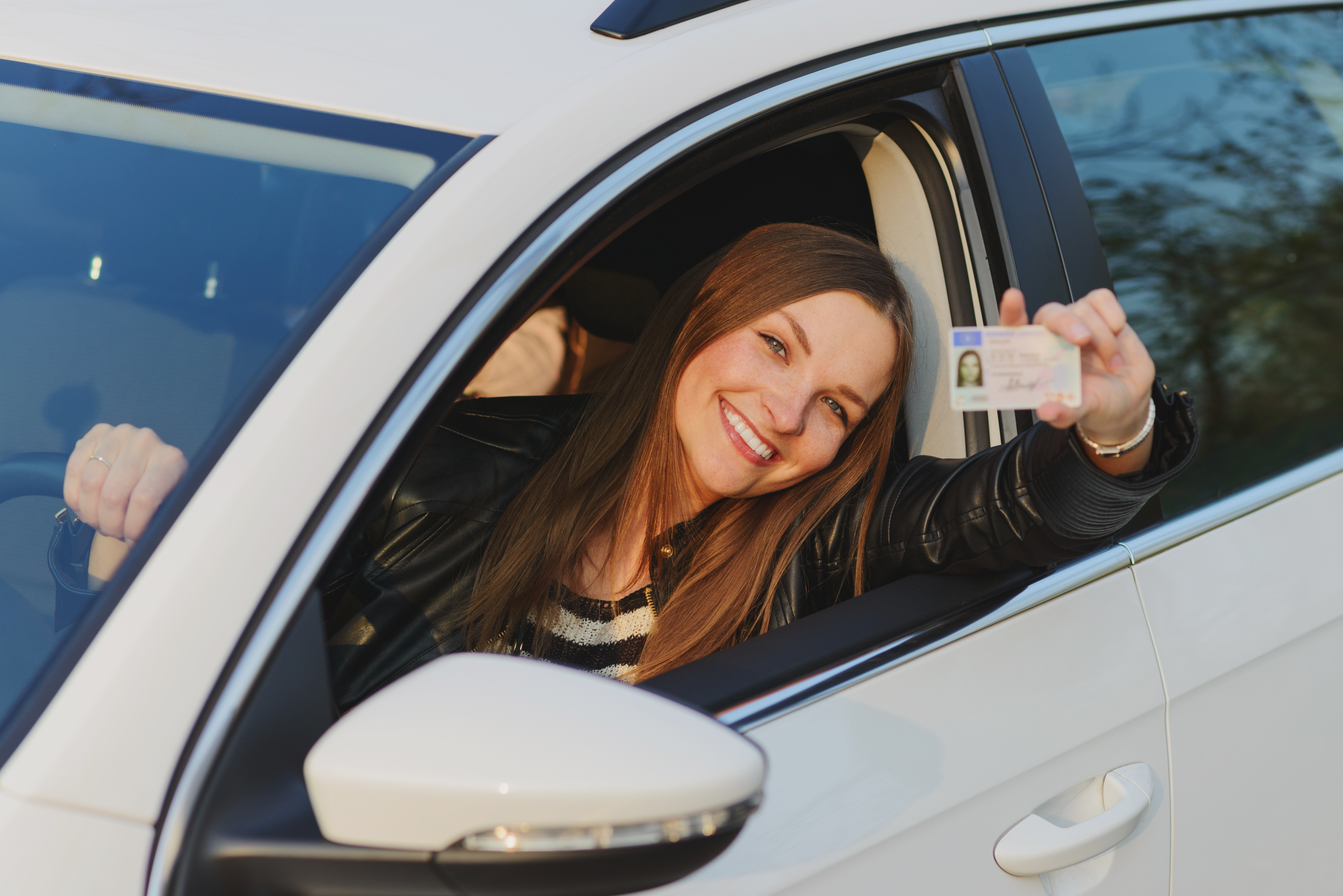 Foto de una mujer saludando desde un auto con su licencia